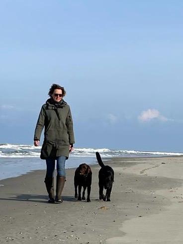 Nanda wandelend met honden op het strand